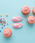 Pink cupcakes with sprinkles on a light blue background