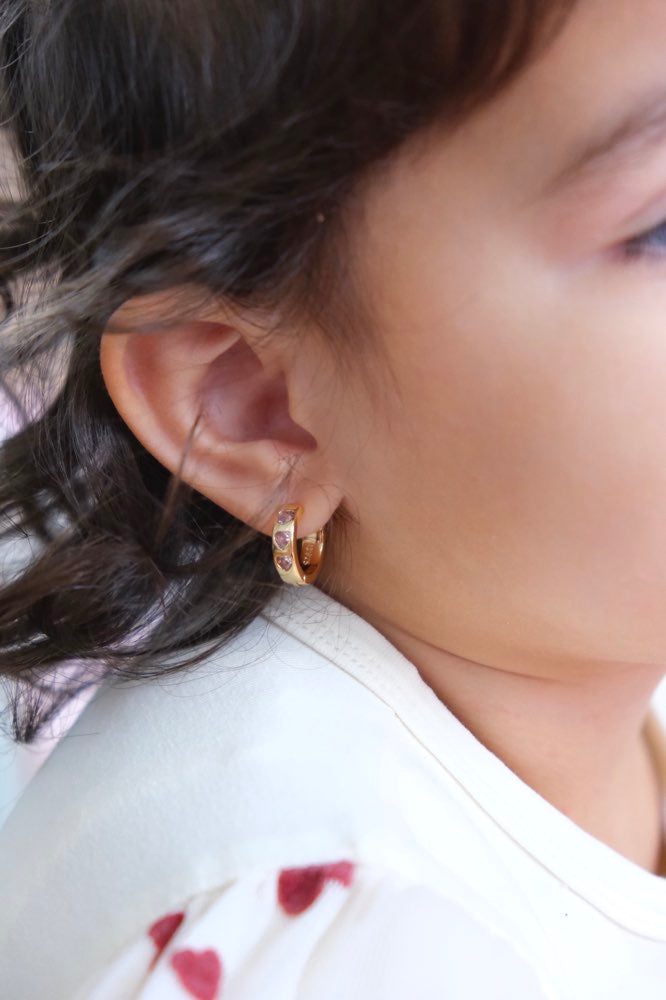 Close-up of a kid wearing gold hoop earrings 