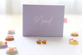 Bee-shaped earrings in front of a 'Mood' branded box on a white background