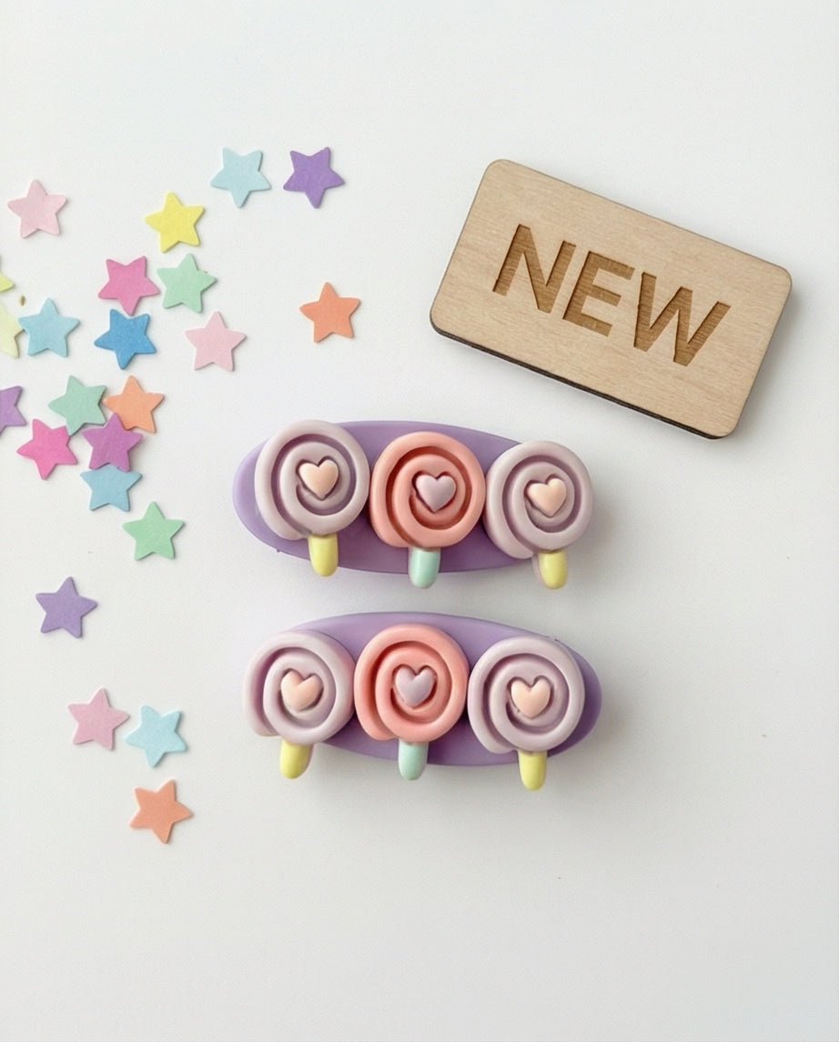 Colorful hair clips with heart designs on a white background with 'NEW' sign and star-shaped decorations.
