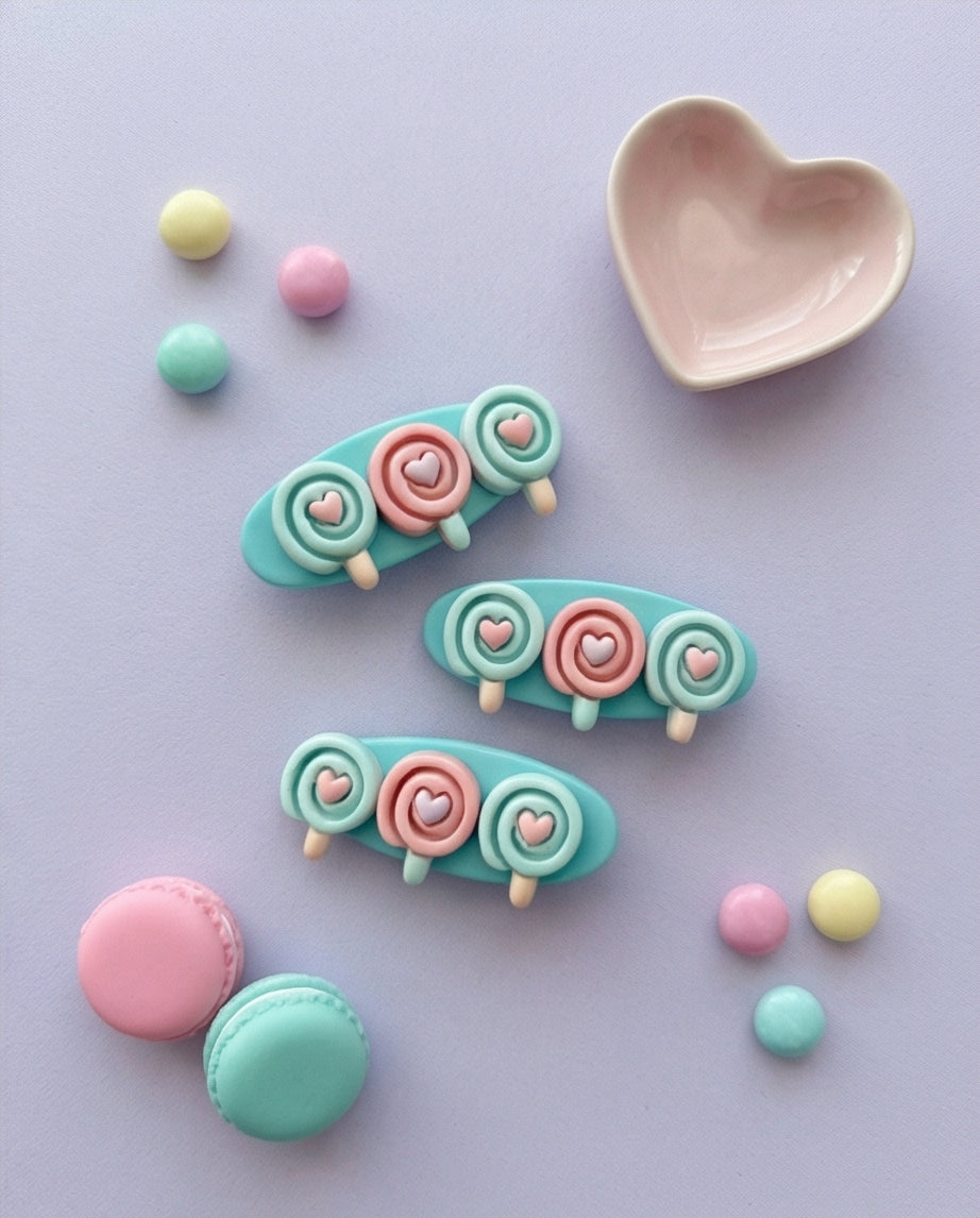 Pastel-colored hair clips with heart and flower designs on a light purple background.