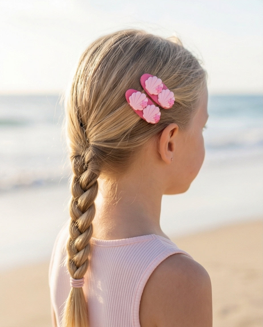 Child with braided hair and pink floral hair clips on a beach
